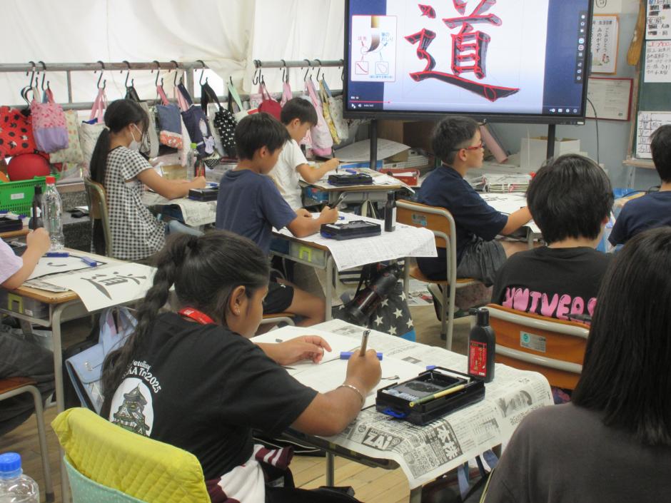 教室で習字を練習する小学生たち