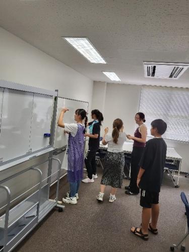 ホワイトボードに英語を書く大学生たち